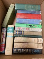 Photo showing the whole lot of 13 classic hardcover books in a cardboard box, arranged side by side and stacked.