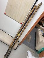 Photo showing all five hockey sticks leaned against a wall, displaying overall condition and variety of designs