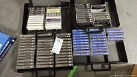 Four black plastic cases filled with assorted cassette tapes organized in rows.