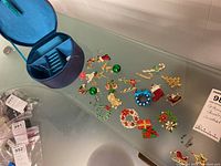 Full lot showing satin jewelry box and assorted Christmas themed costume jewelry pieces spread on table surface.