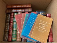 Overhead view of box containing ten leather bound hardcover volumes and six colored softcover pamphlets.