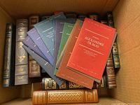 Overhead view of assorted smaller Franklin Library volumes fanned out over larger spines in a box.