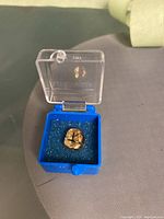 Top‐down view of gold crown seated on blue foam inside clear box