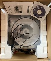 Turntable in protective Styrofoam with USB cable, instruction manual, and installation CD visible.