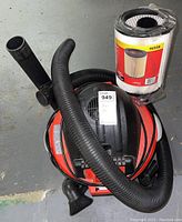 Full view of RIDGID shop vacuum with hose and attachments, replacement filter wrapped in plastic next to vacuum.