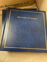 Blue hardcover binder with gold lettering 'THE STORY OF CANADA' on the front cover.