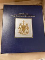 Blue box with gold embossed Canadian coat of arms and text reading 'Canada 125 The Canadian Experience'.