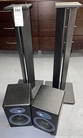 Two black Audioengine speakers on floor in front of two black wood speaker stands