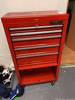 Front view of red tool chest showing five drawers and lower shelf.