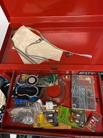 Photo of open toolbox drawer showing assorted electrical wires, nails, screws, hardware fasteners, light bulbs, and some packaged items