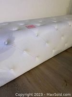 Side view showing white vegan leather surface with button tufting detail.