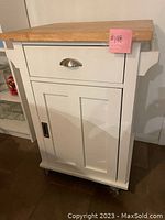 Front view of white kitchen island with drawer, cabinet and butcher block top. Pink price tag $198 attached.