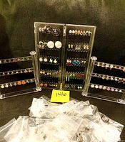 Photo showing clear earring racks with multiple pairs of stud earrings in various colors and designs including round, square, and pearl shapes.