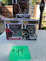 Three Funko POP vinyl figures in their unopened boxes: Tupac Shakur wearing orange glasses and beige outfit, Snoop Dogg in red, and Takeoff in dark attire with white glasses.