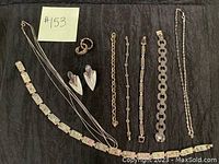 Top view of entire jewelry assortment showing bracelets, rings, earrings, and necklace laid out on dark fabric.