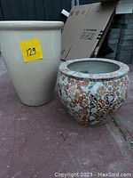 Two large ceramic plant pots: one plain cream tall pot, one colorful round pot with floral and animal motifs