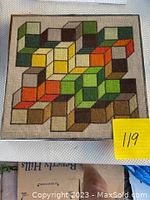 Front view of framed needlepoint art with colorful geometric cube pattern