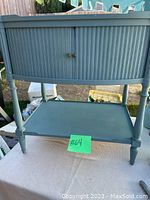 Front view of one teal painted nightstand showing tambour doors, turned legs and lower shelf