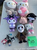 Overview of all plushies and keychains displayed on a surface, including Hello Kitty characters and various Sanrio-themed plush toys along with a Jason plush figure.