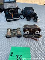 Top down view showing Polaroid camera and three binoculars on textured surface