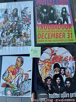 Four posters: one colorful illustrated band image, one Motley Crue concert poster, one Queen poster with band and crest imagery, one colorful illustration of a drummer.