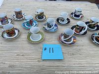 Twelve espresso cups and saucers displayed in three rows, each set with unique colorful abstract or geometric pattern