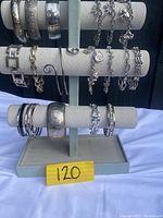 Photo of silver toned bracelets variety shown on white display stand with three horizontal bars.