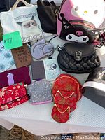 Overview of entire lot showing all items spread on a table in sunlight, including bags, wallets, pouches, and coin purses.