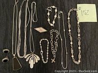 Full view of the sterling silver jewelry lot showing various necklaces, bracelets, earrings, pendants, and a brooch on a black fabric background.