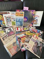 Overview photo of Beatles-related books, magazines, vinyl, and newspapers arranged on a couch.