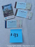 Three vintage Disneyland ticket stubs and a guide booklet laid out on a textured surface.