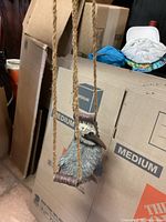 Pelican hanging figure shown hanging by natural rope in front of cardboard boxes, detailed carved texture and paint visible.
