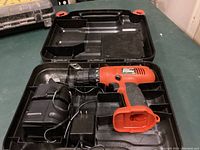 Orange and black Fire Storm 12V Black & Decker cordless drill along with battery and charger inside black carrying case.