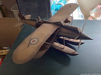Overall top and side view showing the entire seaplane tin model, floats, dual propeller, and the pilot figure attached in the cockpit.