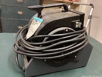 Side/angled view of the blower showing handle and overall shape with coiled power cord