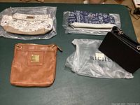 Four Miche bags and covers laid out on table including tan bag and three bag covers