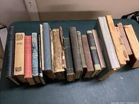 Top view of 20 old books arranged side by side showing condition and titles on spines