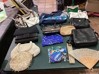 Full lot overview showing various purses, clutches, bandanas, a fan, and face masks arranged on a table