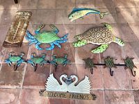 Top view of the sea theme wall displays including metal marine animals, hooks, wooden swan plaque and rusty thermometer. The photo shows all items arranged on a tiled floor for clear visibility.