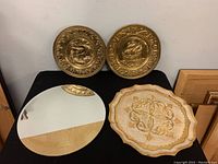 Photo shows pair of 11.5 inch round repousse brass wall art pieces with ship designs above the 15 inch round bevelled edge mirror and the vintage Florentine tray.