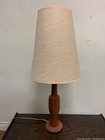 Full view of the Mid-Century Modern teak table lamp with its burlap shade, showing the overall height and form of the lamp.