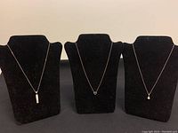 Three sterling silver necklaces displayed on black necklace stands against plain background.