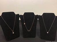 Three 925 silver necklaces displayed on black necklace stands, showing different pendant styles.