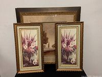 Photo shows two smaller 22x12 inch framed floral prints with bouquets of pink, purple, and white flowers, ornate gold and cream frames, placed in front of a larger framed landscape print.