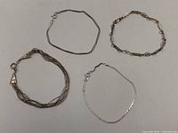 Four different sterling silver 925 bracelets laid out, showing their styles and lengths.