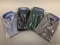 Four men's slim fit dress shirts by Viktor & Muse, packaged in plastic, showing different colors and patterns.
