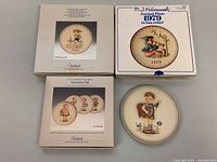 Four vintage Goebel M.J. Hummel bas-relief plates with three original boxes, arranged showing dated plates and Valentine series boxes