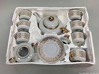 Full tea set items arranged in original styrofoam packaging, showing all cups, saucers, teapot, creamer, and sugar bowl.