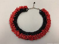 Full view of vintage bib choker necklace displaying chunky red natural coral beads and black glass beads with metal clasp.