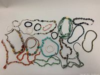 Full layout of 8 stretch bracelets and 12 necklaces showing varied semi-precious stones including jade, lapis lazuli, rose quartz, jasper, and freshwater pearls.